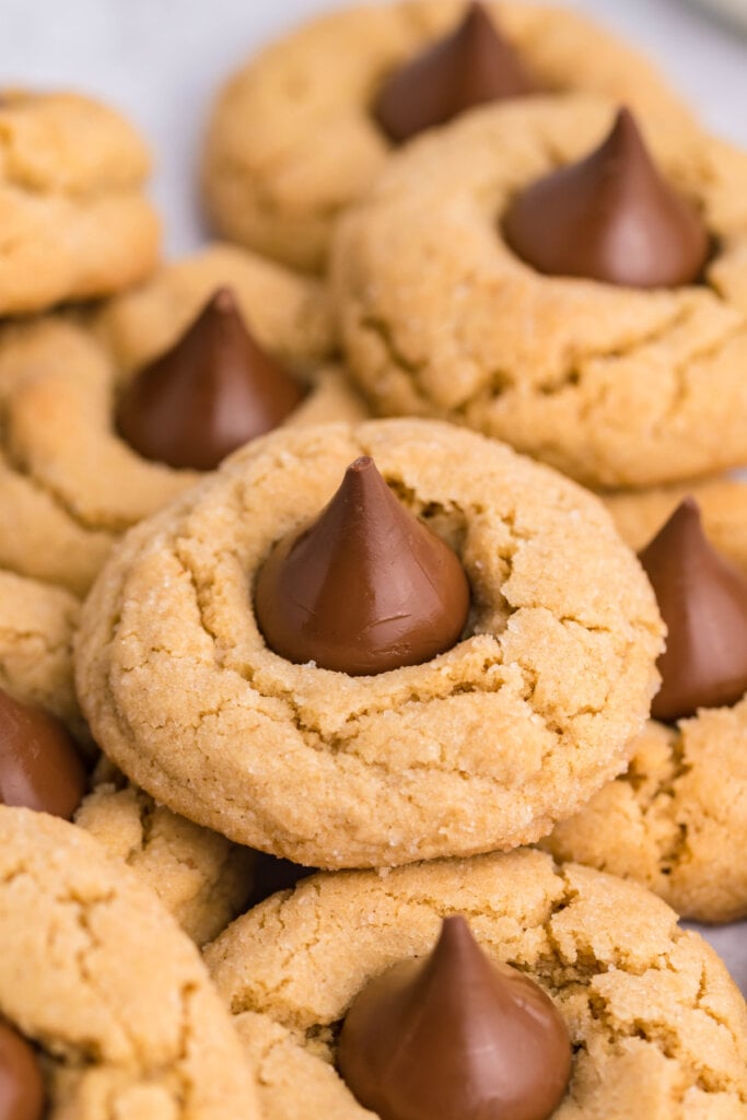 several peanut butter blossoms cookies scattered and stacked