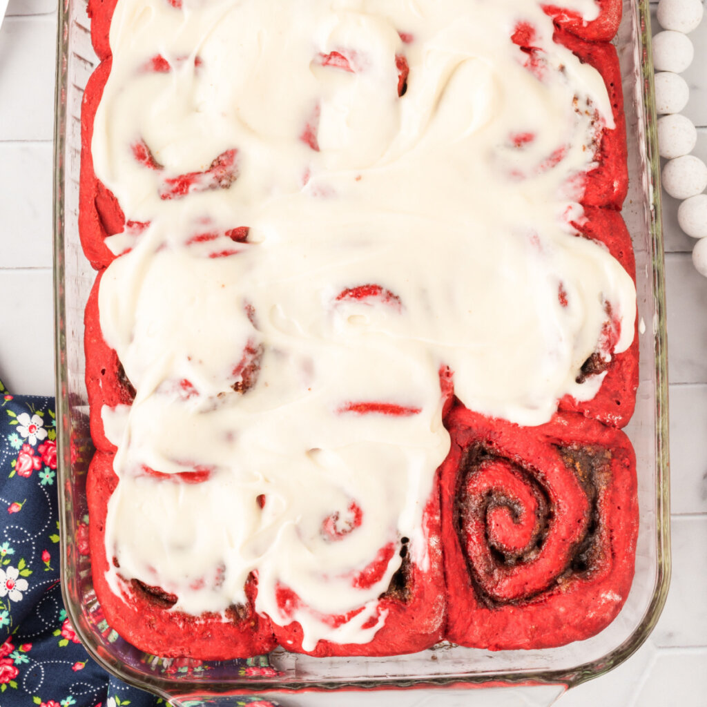 red velvet cinnamon roll swith cream cheese icing in glass pan
