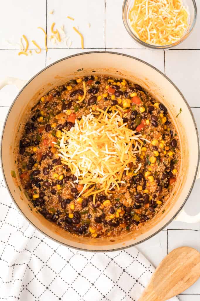 quinoa, black beans, corn, and vegetables mixed with enchilada sauce in a white pot