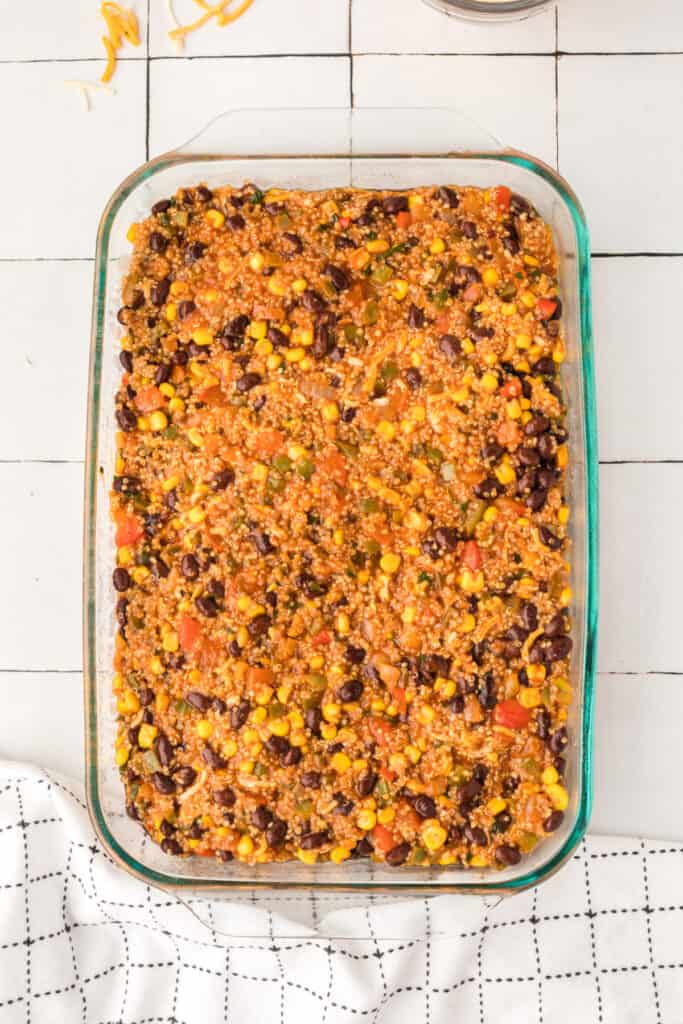 quinoa, black beans, corn, and vegetables spread evenly in a glass baking dish