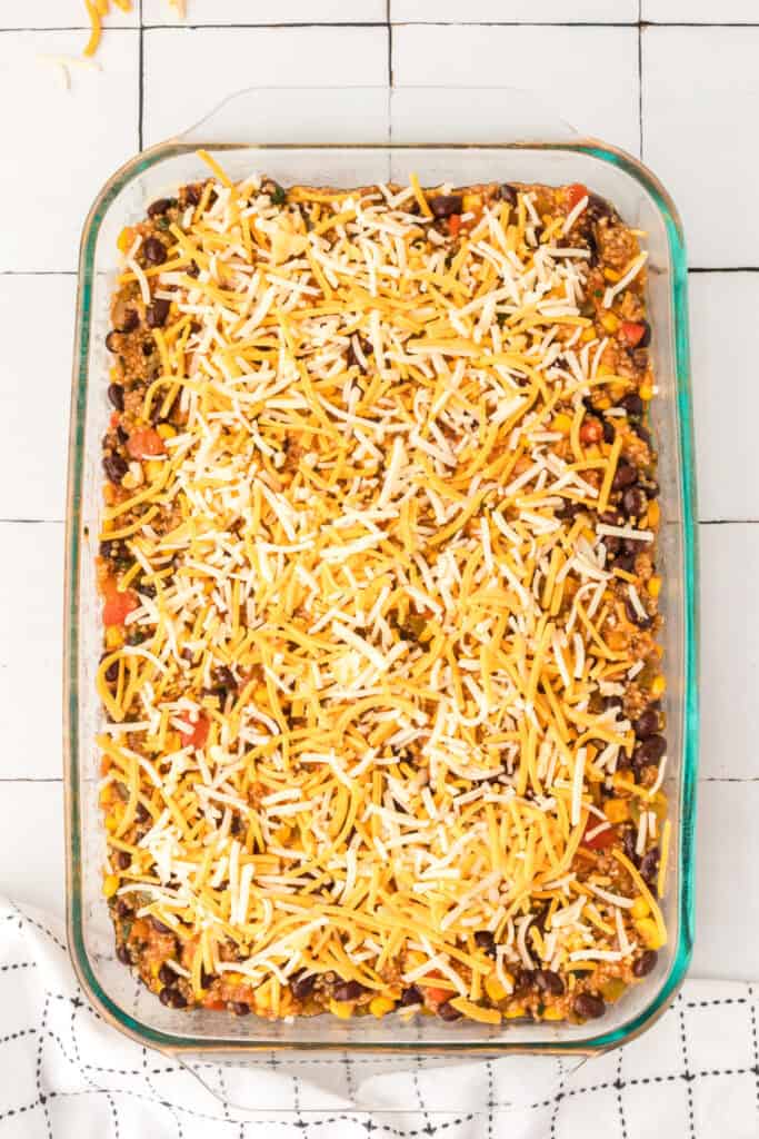 shredded cheese covering quinoa and black bean casserole in a glass baking dish