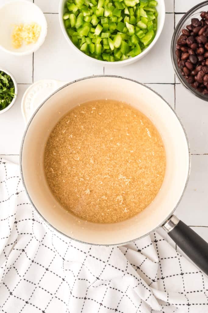 uncooked quinoa soaking in water in a saucepan for vegetarian enchilada quinoa casserole