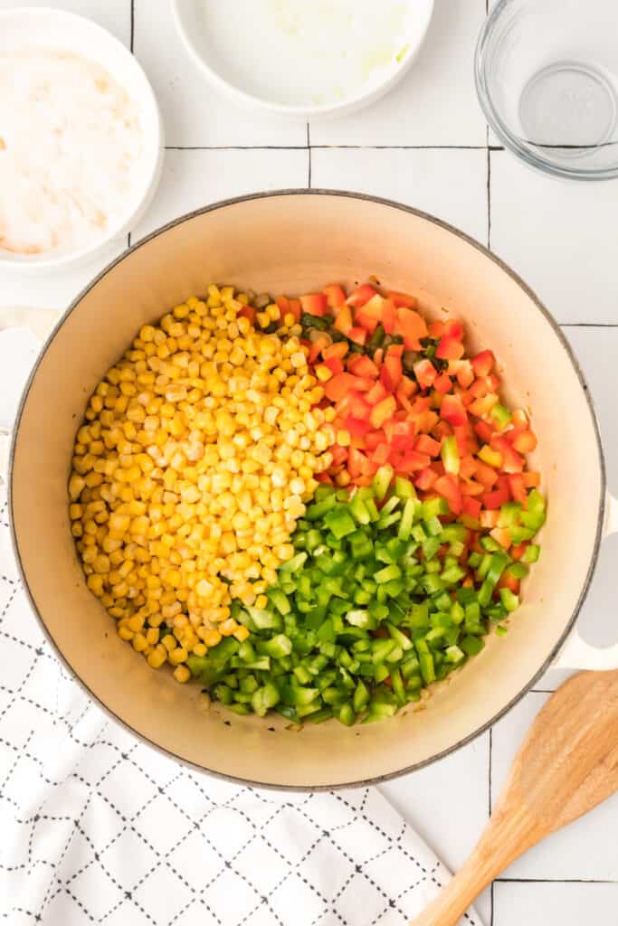 bell peppers and corn added to pot for vegetarian enchilada quinoa casserole