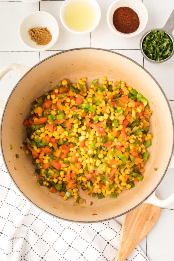 spices and cilantro added to vegetables in pot for vegetarian enchilada quinoa casserole