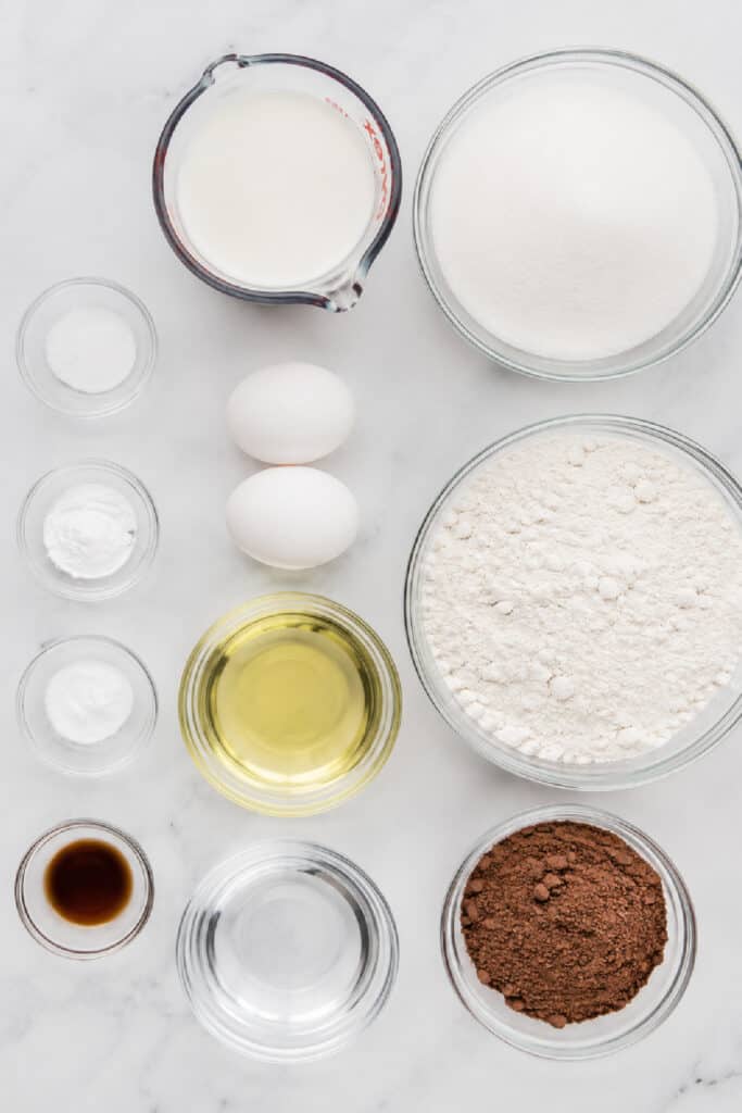 Ingredients for homemade chocolate cupcakes arranged on a white marble surface
