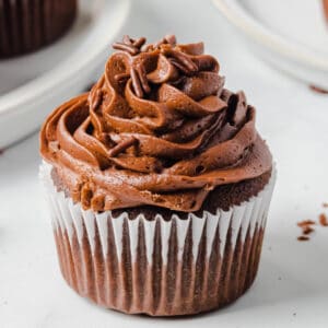 Close-up of a homemade chocolate cupcake topped with chocolate buttercream frosting and chocolate sprinkles
