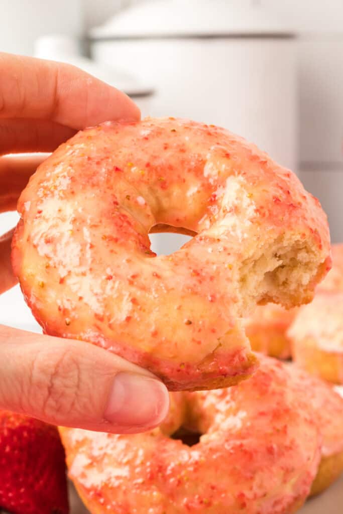hand holding a donut with a bite taken out of it