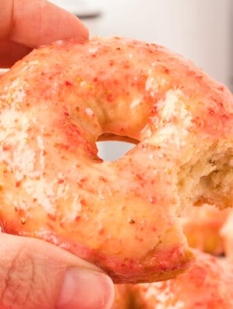 hand holding a vanilla cake donut with strawberry galze