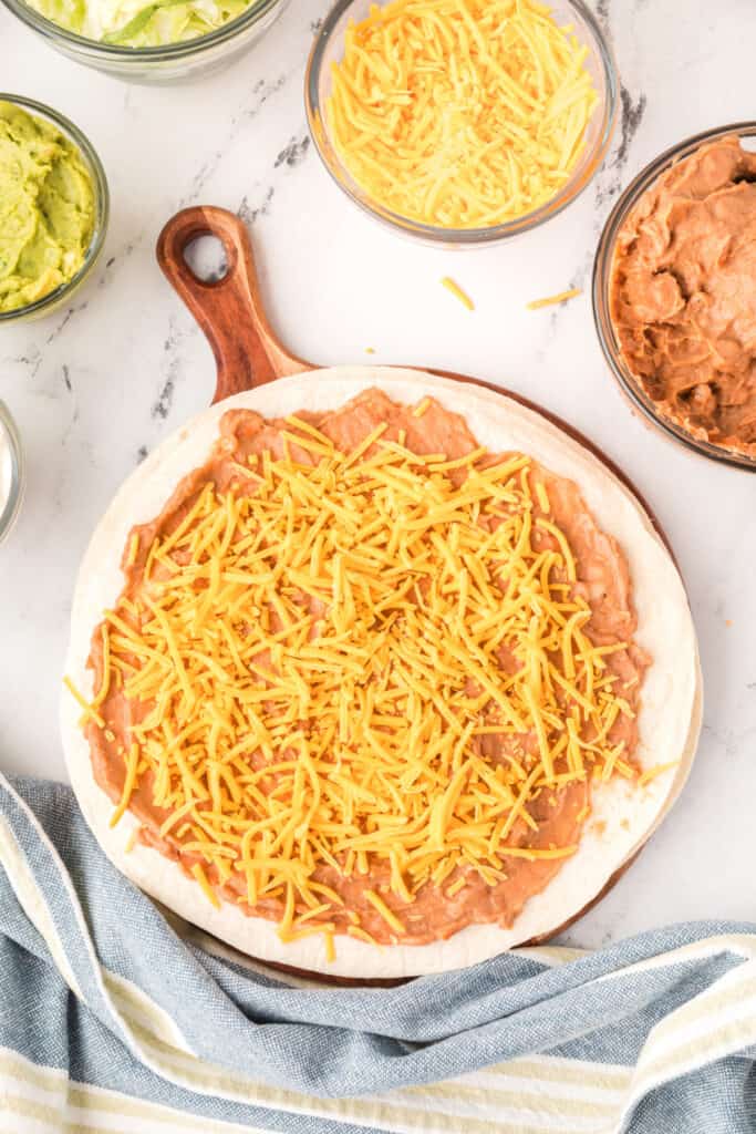 flour tortilla spread with refried beans topped with shredded cheddar cheese