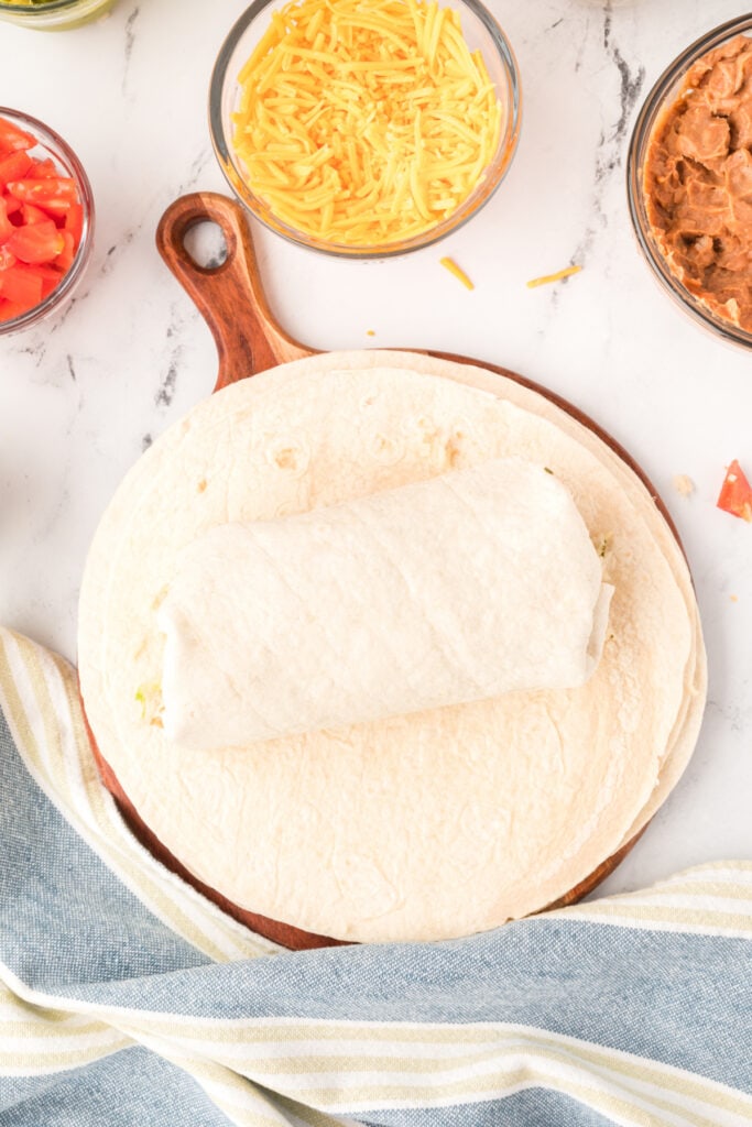 burrito rolled up on a tortilla on a wooden board