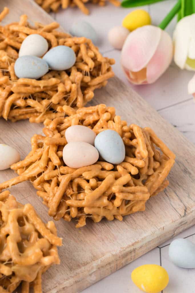 bird nest cookies on wooden board with spring flowers in the background