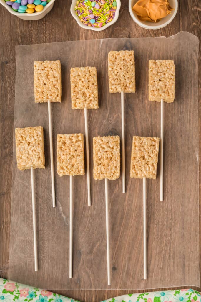 rice krispies treats skewered onto sucker sticks and resting on waxed paper