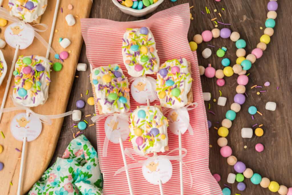 several spring rice krispies treats pops on wooden table with pink towel