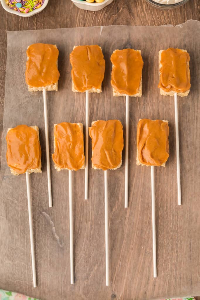 peanut butter mixture on rice krispies treats pops