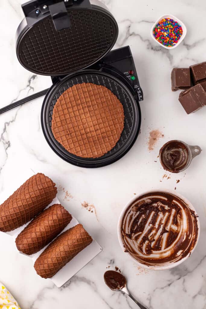 Freshly baked chocolate waffle shell with finished taco shells cooling on a taco holder.
