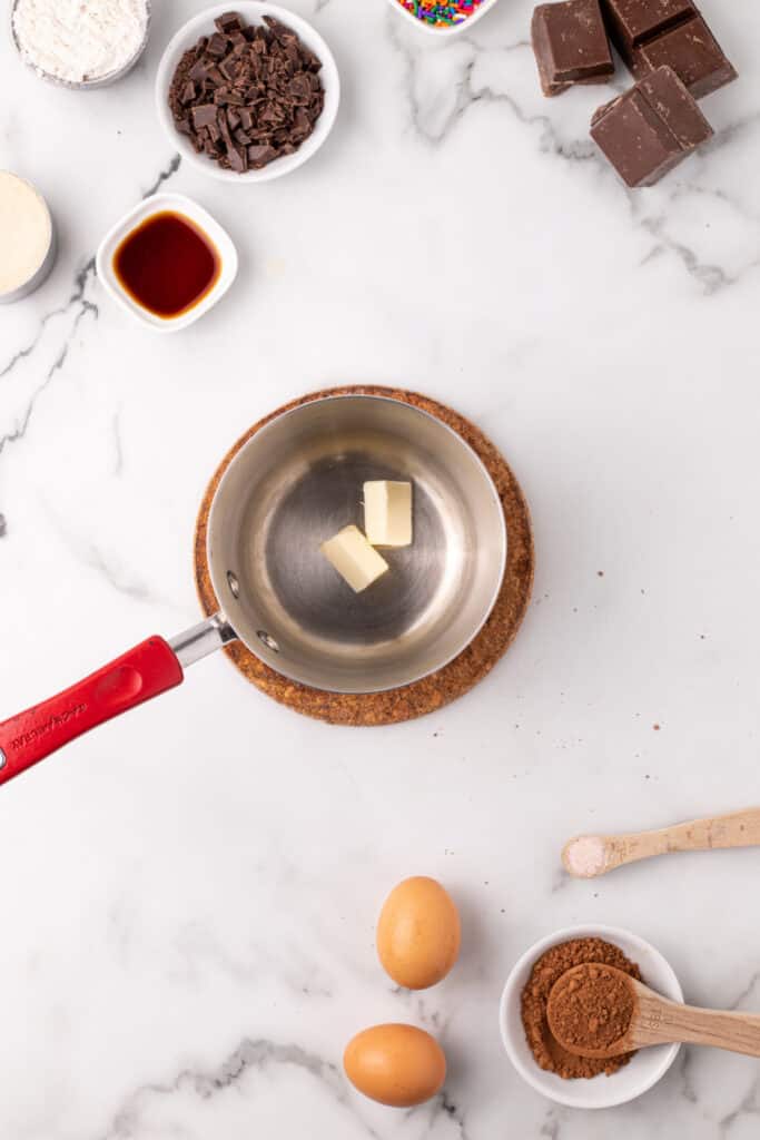 Butter melting in a small saucepan while the ingredients for homemade Choco-Tacos are arranged around the work surface.