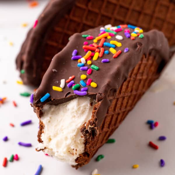 Homemade Choco-Taco with a bite missing, featuring vanilla ice cream, chocolate coating, and rainbow sprinkles.