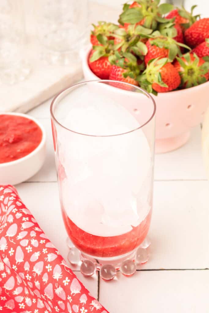 Ice added over the strawberry mixture when assembling homemade Freckled Lemonade.