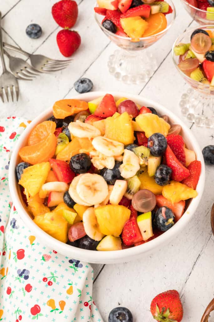 rainbow fruit salad with honey citrus dressing in white bowl