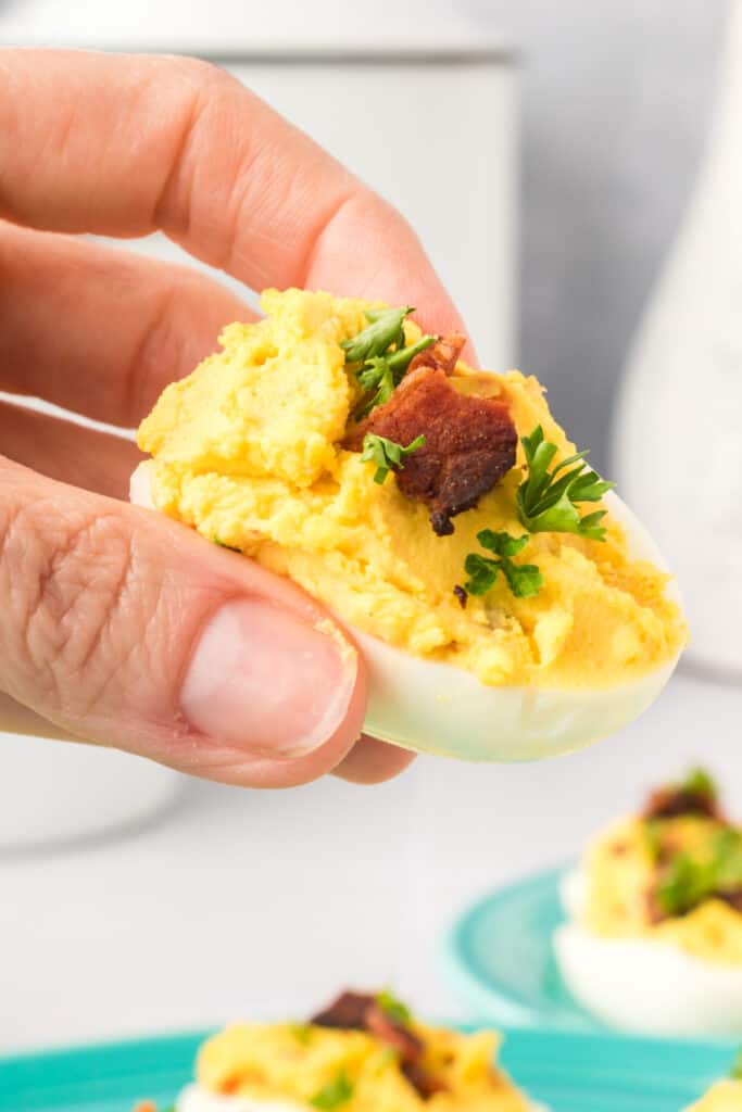 hand holding a bacon cheddar deviled eggs