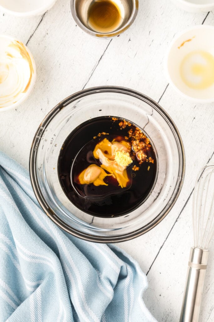 glass bowl with soy sauce, peanut butter, oil, and ginger before mixing