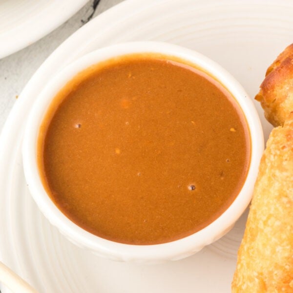 square image of thai peanut sauce in bowl with egg rolls