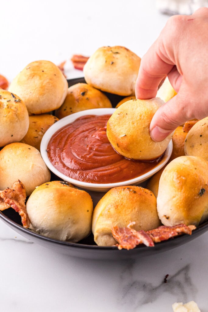 bacon bomb being dipped into pizza sauce