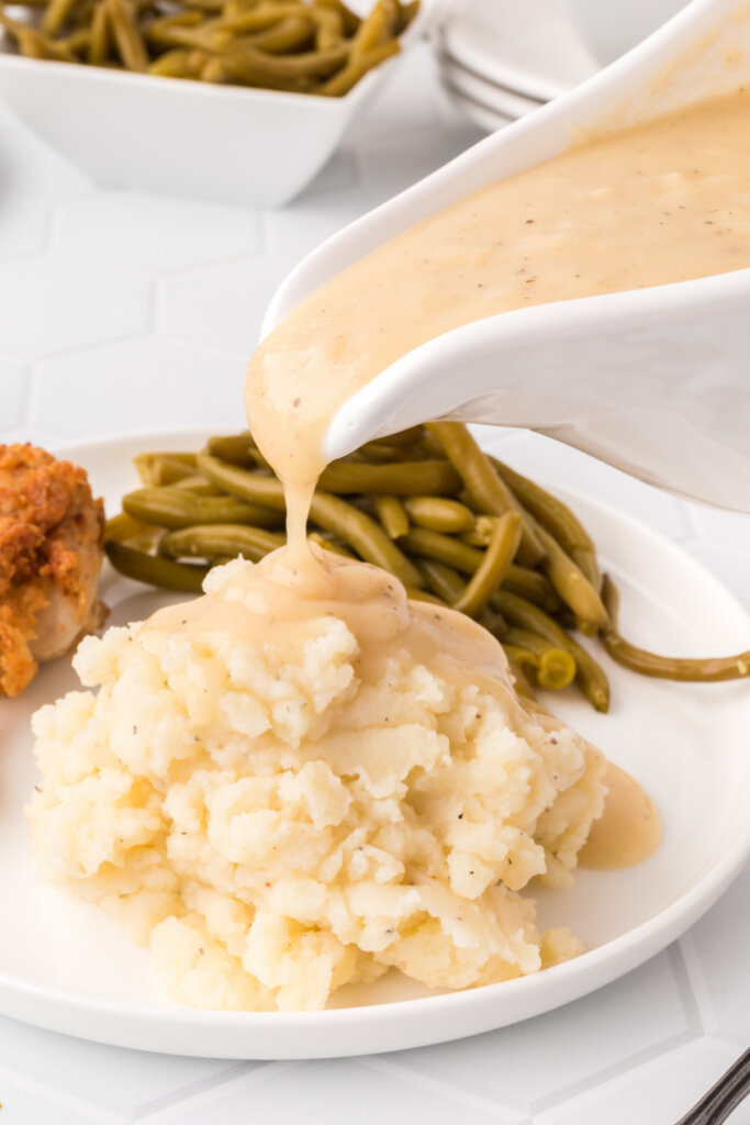 chicken gravy being poured over mashed potatoes