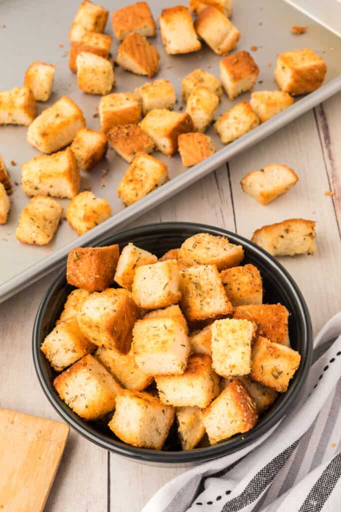 homemade garlic parmesan croutons in bowl and on baking sheet