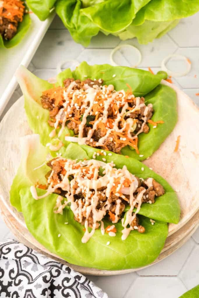 close-up of Asian Pork Lettuce Wraps in butter lettuce with toppings and sauce drizzle