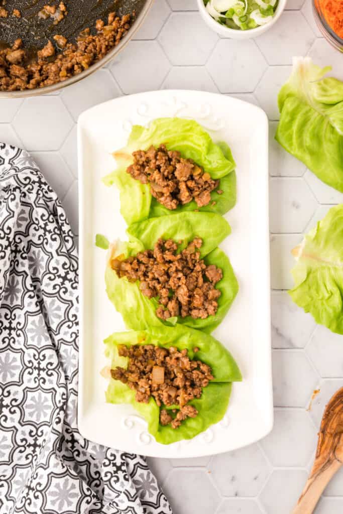 ground pork mixture spooned into butter lettuce leaves for Asian Pork Lettuce Wraps