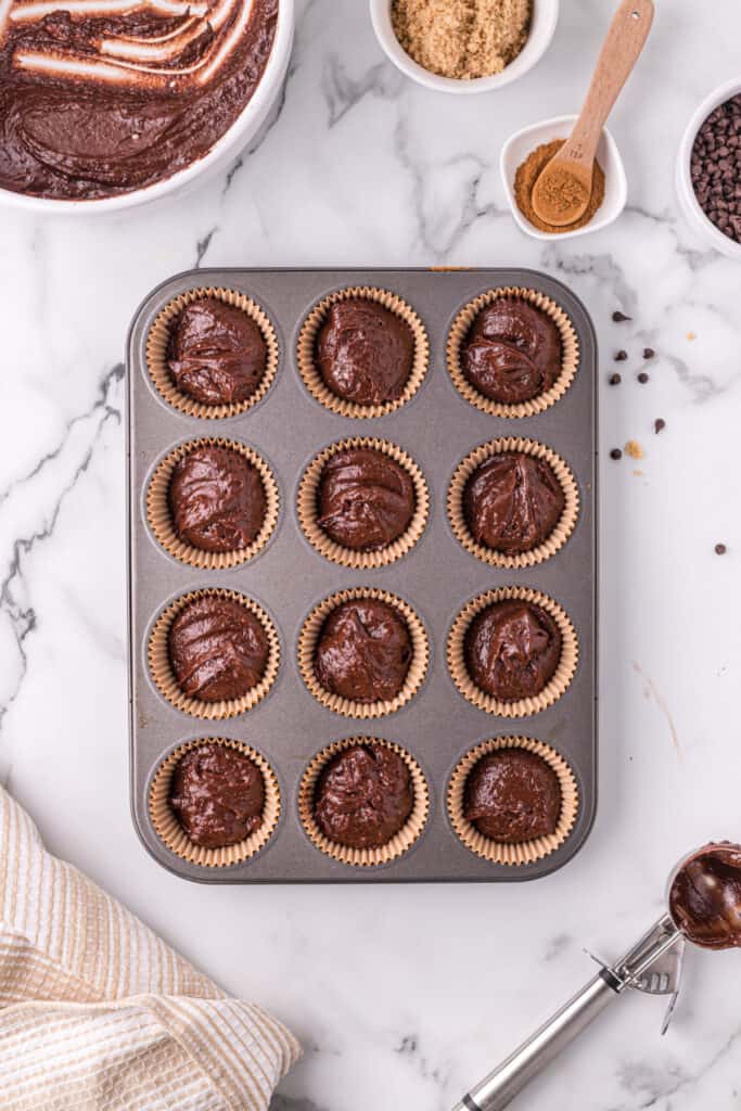 Chocolate muffin batter scooped into lined muffin pan