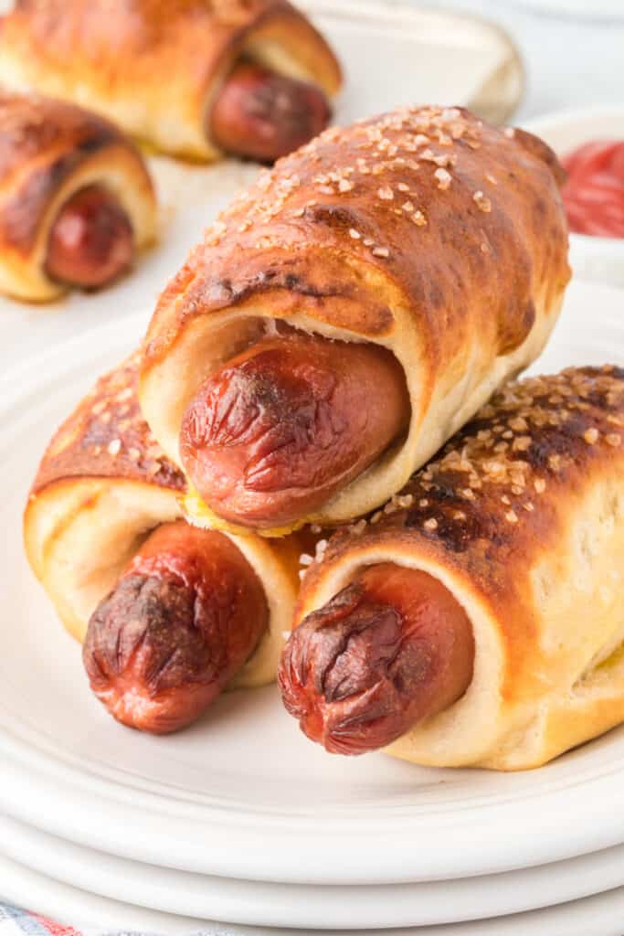 three pretzel dogs stacked on a plate