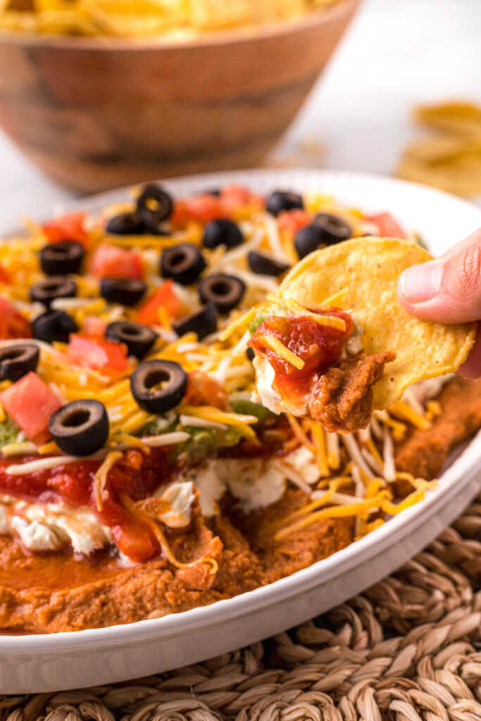 tortilla chip scooping 7 layer bean dip