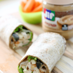 PB Apple Chicken Salad Wraps with the ends opened up to see the ingredients. Close up with a jar of Jif in the background.