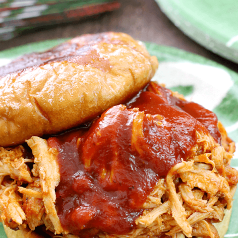 Slow Cooker BBQ Pulled Pork Sandwich close up on a plate with the top off.