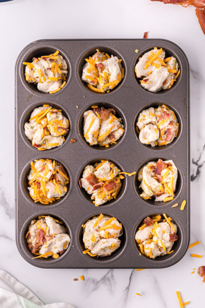 cheddar bacon ranch pull apart rolls in muffin tin before being baked