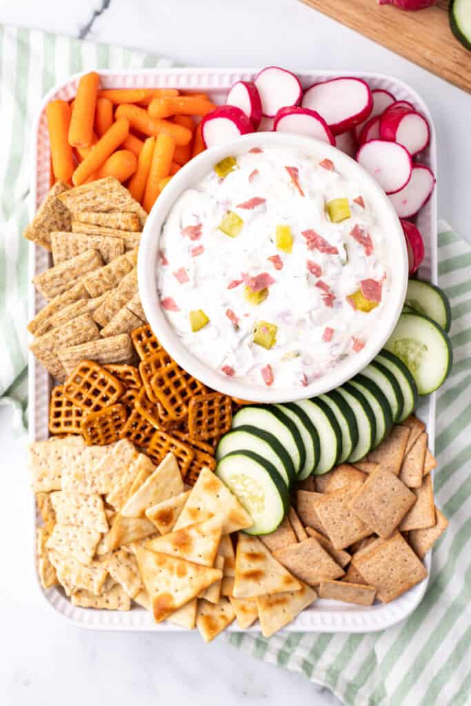 Overhead of full appetizer platter with dill pickle wrap dip, crackers, veggies, and pretzels
