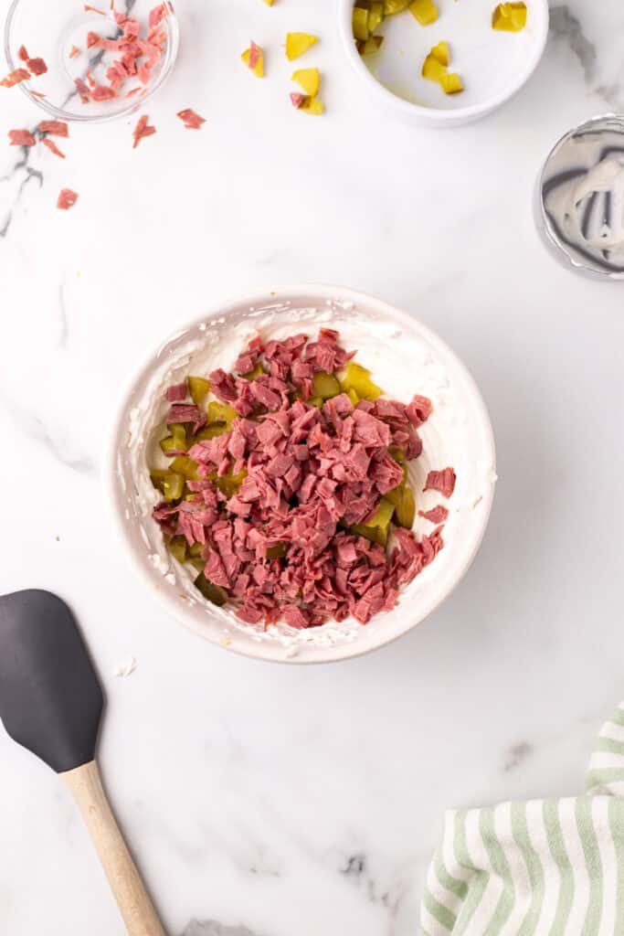 Dried beef added to the mixing bowl with pickles and cream base