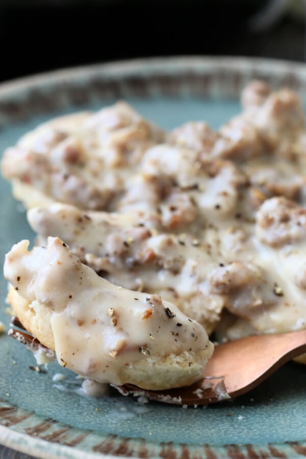 sausage gravy and biscuits on blueish-teal plate