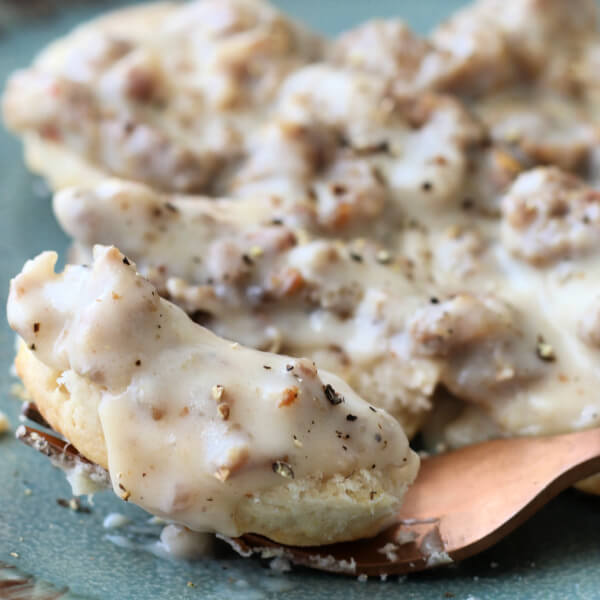 closeup of sausage gravy over biscuits on a fork