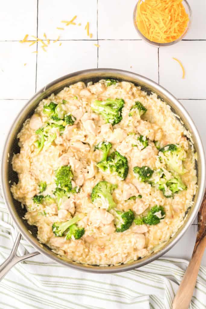 Finished Cheesy Chicken Broccoli Rice Skillet with chicken, broccoli, rice, and melted cheddar cheese in a large skillet