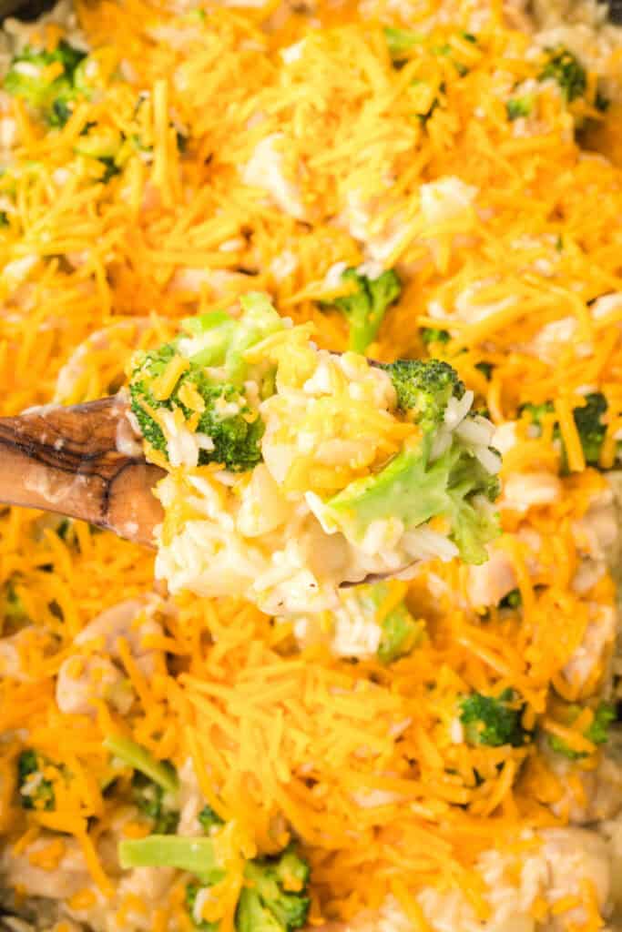 Spoonful of Cheesy Chicken Broccoli Rice Skillet with melted cheddar cheese, broccoli, chicken, and creamy rice