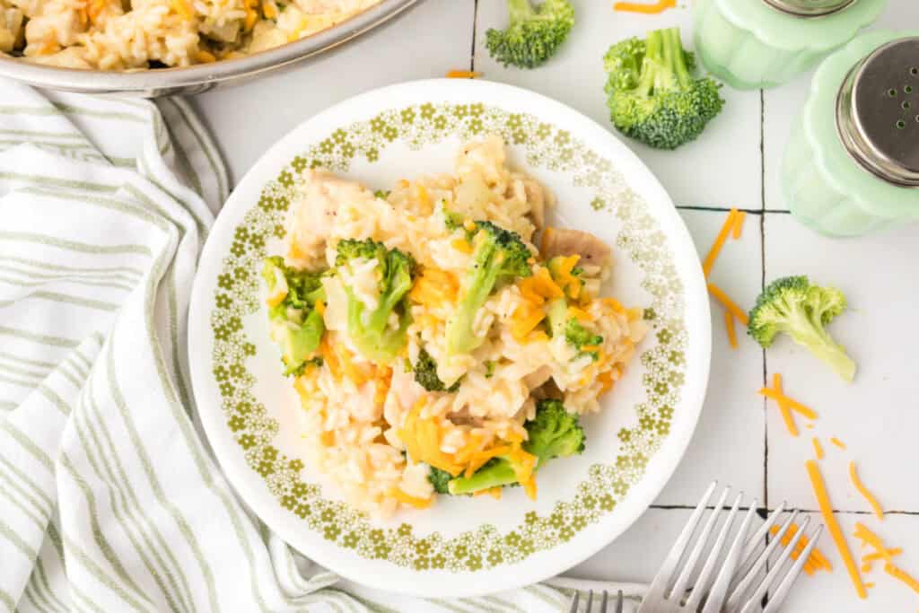 Cheesy Chicken Broccoli Rice Skillet served on a white plate with broccoli, chicken, creamy rice, and melted cheddar cheese