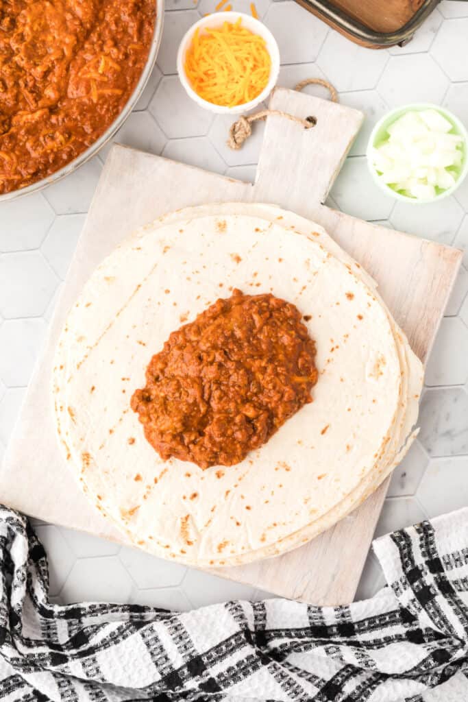 Chili Cheese Burrito filling spooned onto a large flour tortilla before adding toppings and rolling.