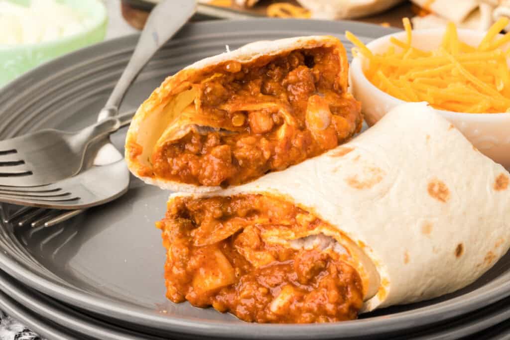 Close-up of a sliced Chili Cheese Burrito filled with seasoned beef, refried beans, cheddar cheese, and diced onion.
