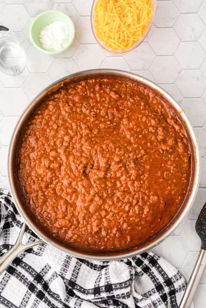 Thickened Chili Cheese Burrito filling cooking in a large skillet after the refried beans have been incorporated.