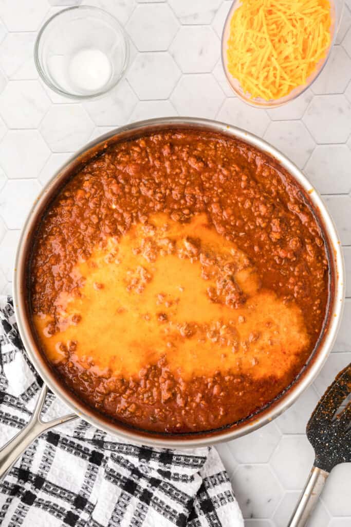 Melted cheddar cheese added to the Chili Cheese Burrito filling in a large skillet.