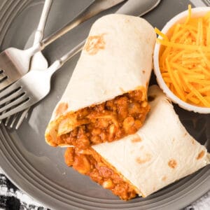 Square-cropped image of a sliced Chili Cheese Burrito showing the cheesy beef and bean filling on a gray plate.