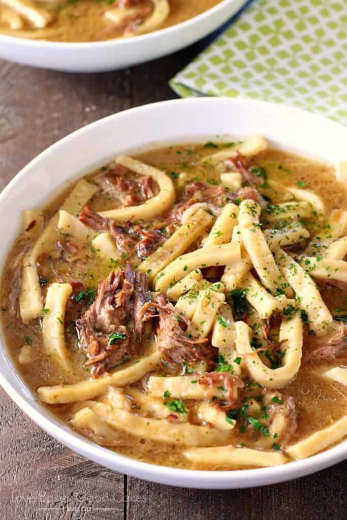 Close-up of tender shredded beef and home-style egg noodles in rich savory broth